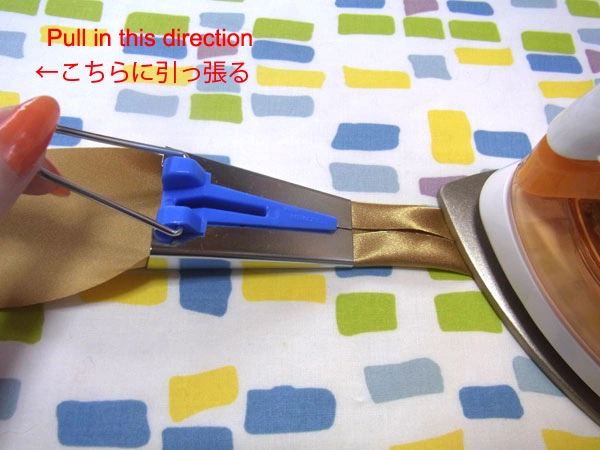 Pulling golden satin through a tape maker tool